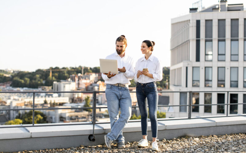 Business colleagues discussing work on rooftop with laptop Business colleagues discussing work on rooftop with laptop