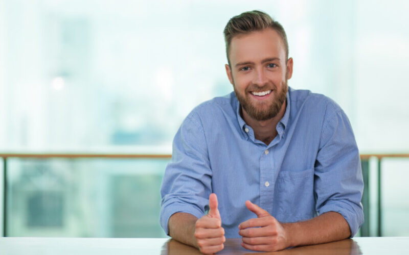 Smiling Man Sitting at Cafe Table and Gesturing Smiling Man Sitting at Cafe Table and Gesturing