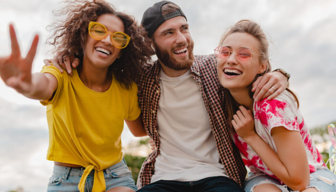 happy young company of smiling friends sitting in park